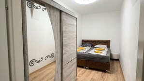 Un dormitorio con cama, armario y luz en el techo.