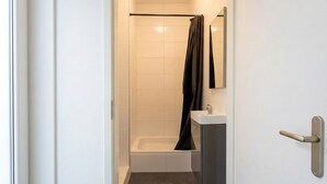 Un baño moderno con ducha, lavamanos y espejo.
