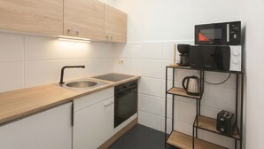 Una cocina compacta con lavamanos, estufa, microondas y una alacena con cafetera.
