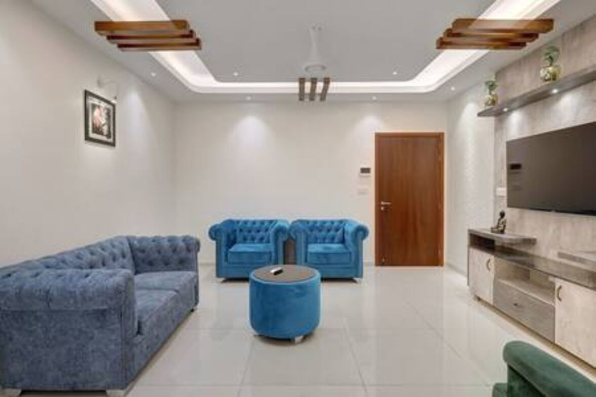 A modern living room with a sofa, ottoman, and a television.