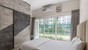 A bedroom with a bed, a wardrobe, and a window with a view of a residential area. - The Urbanite Twins by Stayjadecminr Aster (Bengaluru)
