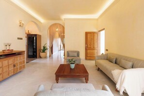 A spacious living area with a wooden coffee table, a beige sofa, a cushioned armchair, and a wooden cabinet. - Westend Apartment by Redolive Racecourse Rd Luxe (Bengaluru)