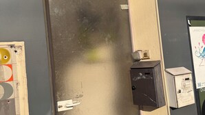 Eine Metalltür mit Griff, eine kleine schwarze Box und ein Poster an der Wand.