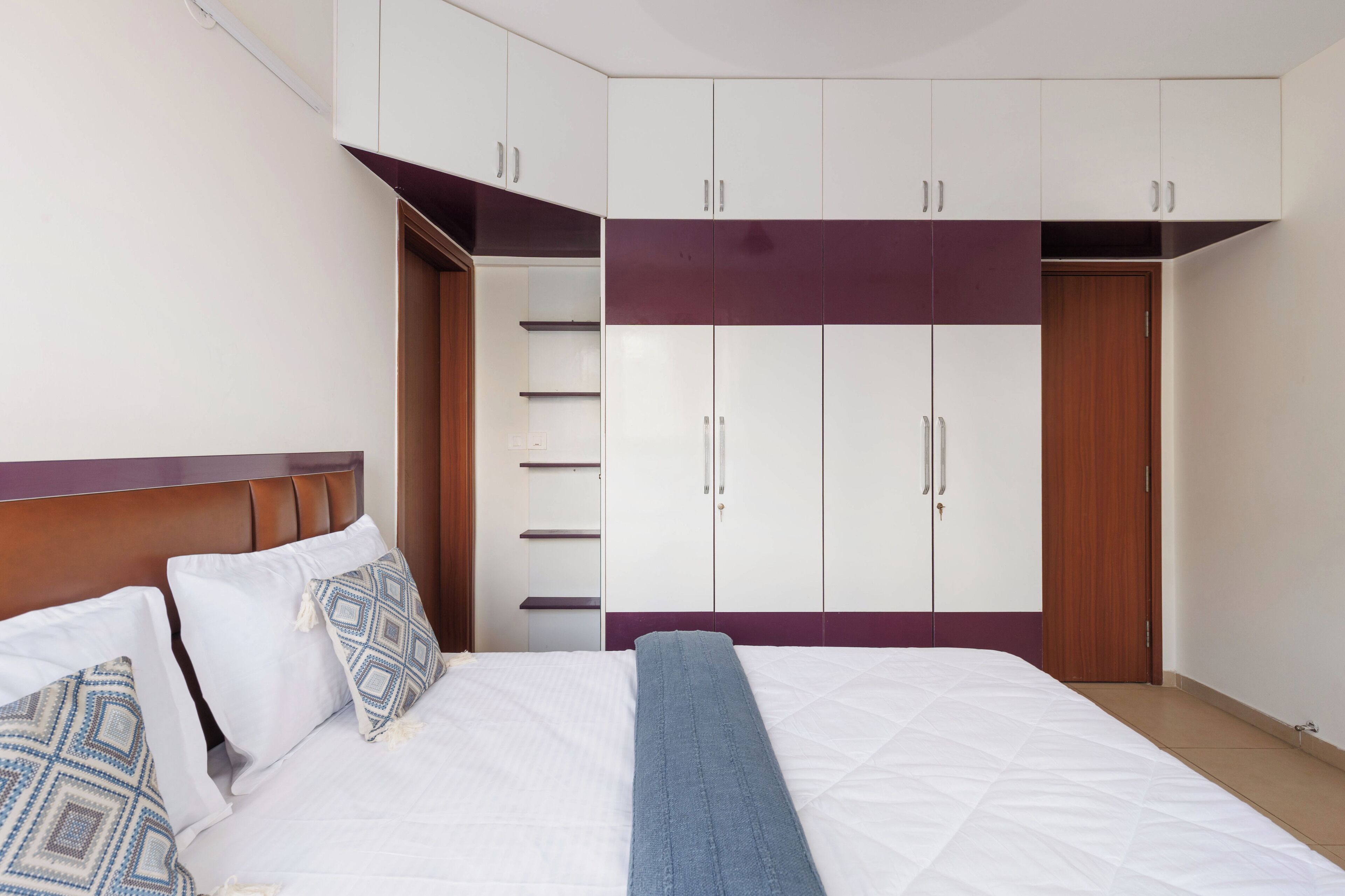 Un dormitorio con cama, almohadas, una colcha, un armario y una puerta.