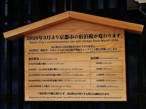 Ein Holzschild mit Informationen zu Änderungen der Kyotoer Übernachtungssteuer ab März 2026.