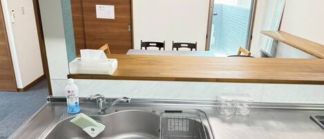 Een koelkast, een magnetron, een kookplaat, kookgerei, borden en bestek