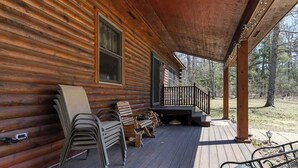 En stuga byggd av trä med en veranda, utomhusmöbler och en trappa som leder upp till en terrass.