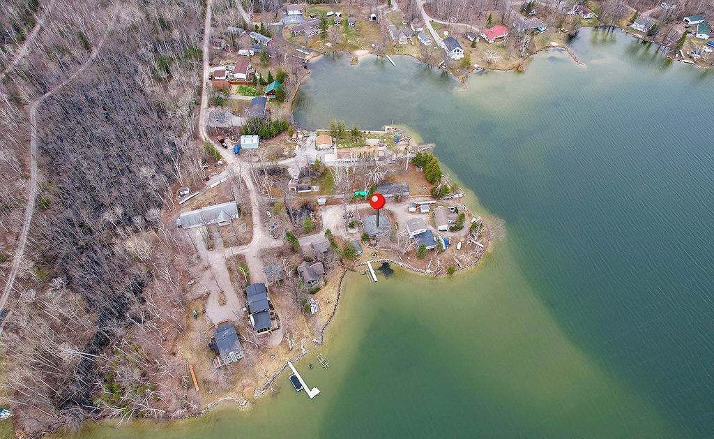 Vista aerea di una proprietà sul lago con diversi edifici, un molo e un segnale rosso.