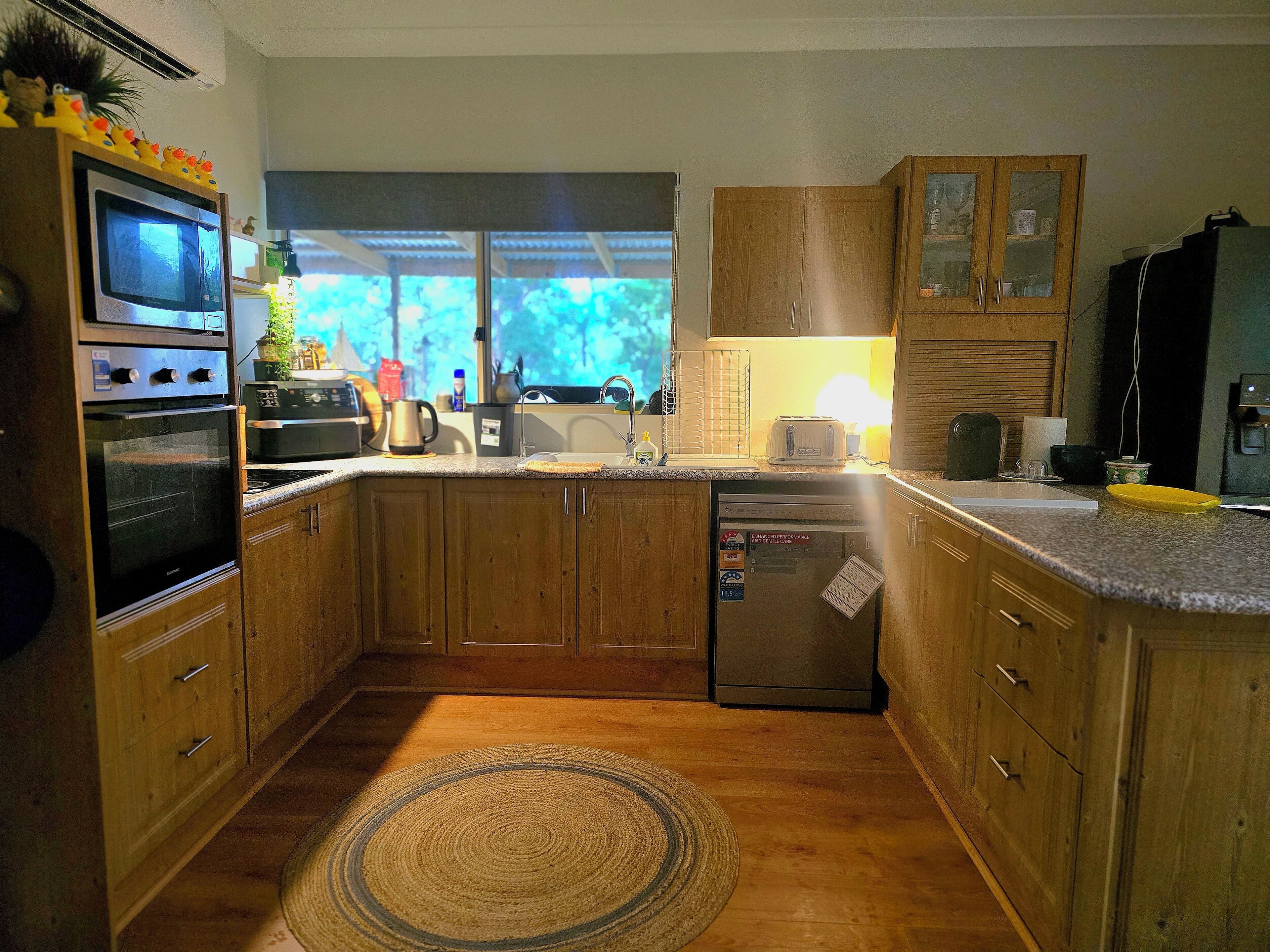 Una cocina con armarios de madera, horno empotrado, refrigerador y ventana con vistas al exterior.