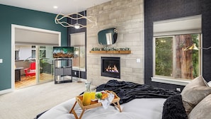 A modern living room with a fireplace, a dining area, and a large window. - Bruno House ~ NFL Luxury Home w AC ~ 2 Hot Tubs ~ Game Room ~ Fam Friendly (Seattle)