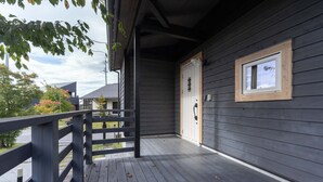 Une terrasse en bois avec une rambarde, une porte et une fenêtre.