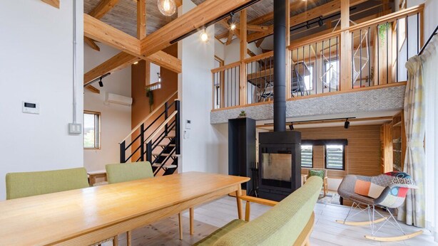 Un vaste espace de vie comprenant une table à manger en bois, un canapé et un poêle à bois noir.