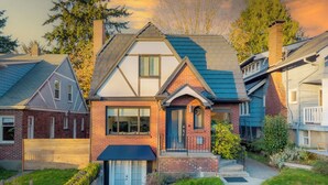 A two-story house with a brick facade, a front porch, and a small garden area. - NFL Spacious Green Lake Home, Dog OK, BBQ/Karaoke (Seattle)