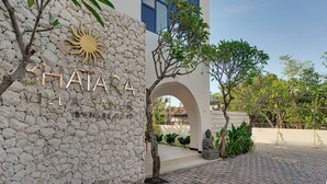A building with a stone wall and a sun-shaped sign. - Bhatara Villa Sanur (Denpasar)
