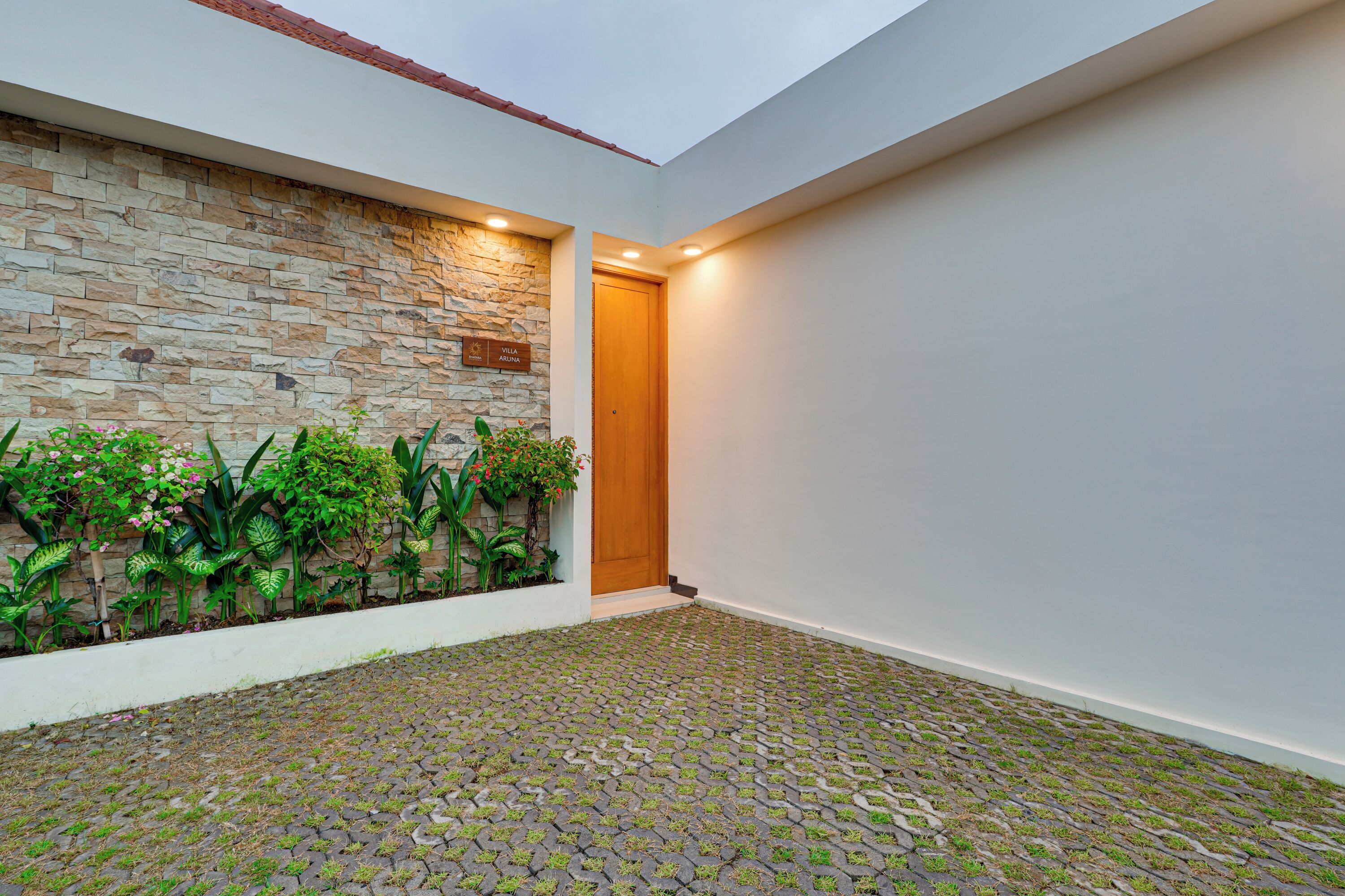 Un edificio moderno con pared de piedra, puerta de madera y piso de baldosas.
