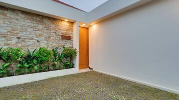 Un edificio moderno con pared de piedra, puerta de madera y piso de baldosas.