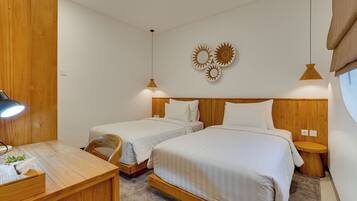 A hotel room with two single beds, a wooden desk with a lamp, and a small table with a tissue box.