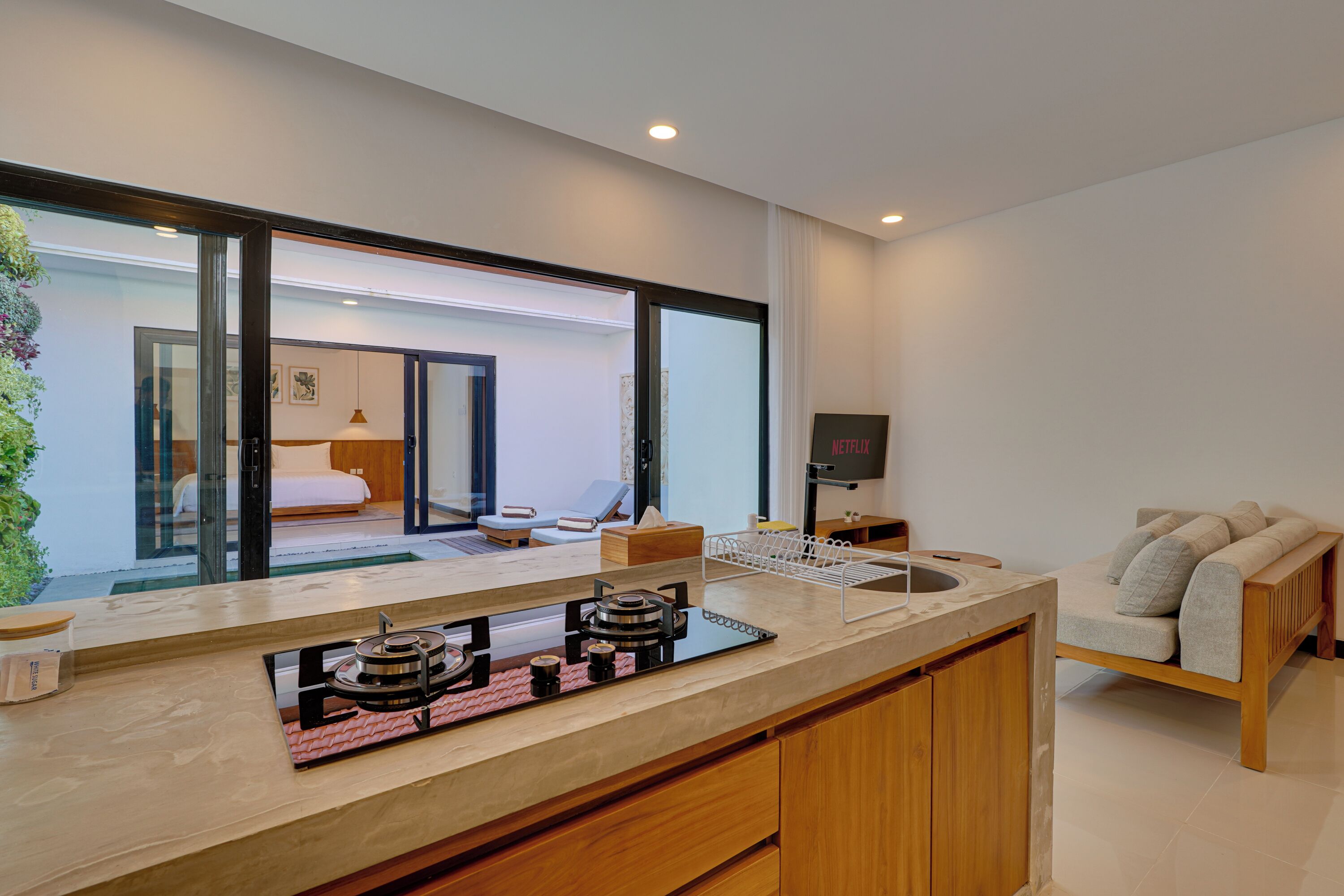 A modern kitchen with a gas stove, a sink, and a countertop. There is a wooden cabinet below the counter.