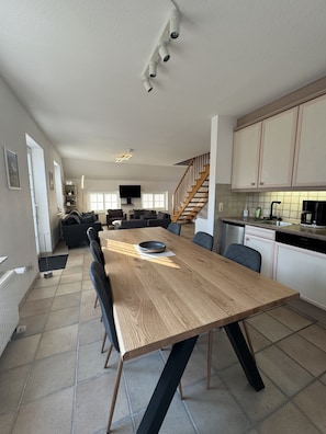 Una cucina moderna con un tavolo da pranzo in legno, sedie nere e una scala che conduce a una zona mansardata.