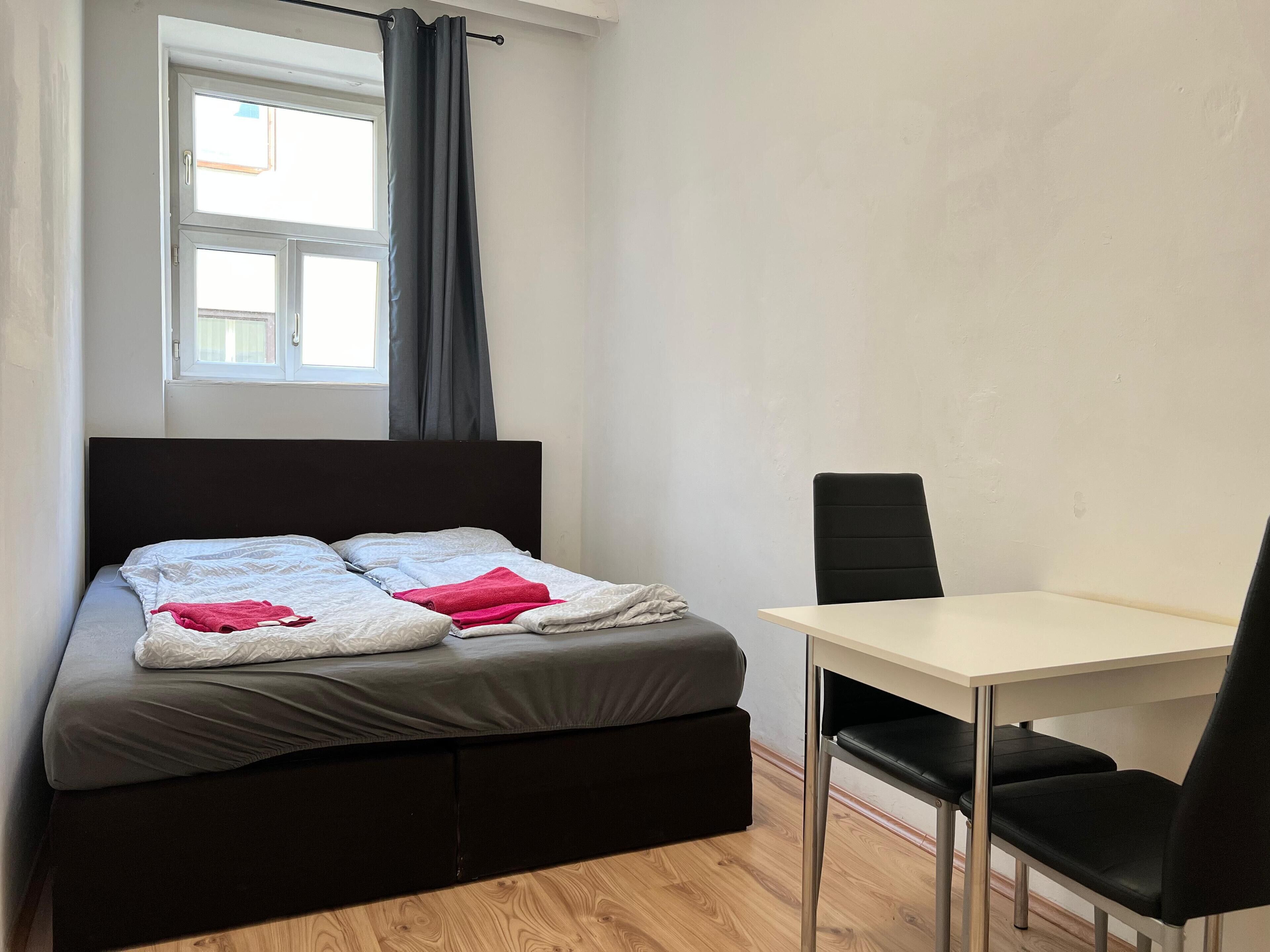 A bedroom with a bed, a desk, and a chair.