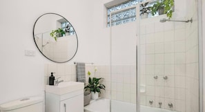Un baño con inodoro, lavabo, espejo y ducha.