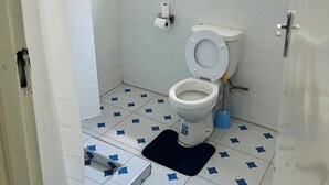 A small bathroom with a toilet, a shower area, and a window. - Cozy 2-bedroom 2-bathroom house in charming Mutare with luxury amenities. (Mutare)