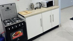 A modern kitchen with white cabinets, a gas stove, a microwave, and a kettle. - Cozy 2-bedroom 2-bathroom house in charming Mutare with luxury amenities. (Mutare)