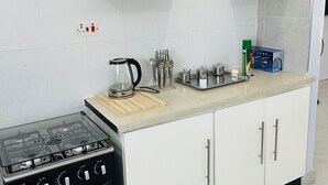 A kitchen with a gas stove, white cabinets, and a countertop with various kitchen items.