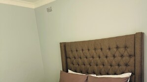 A neatly made bed with a tufted headboard, two pillows, and a grey throw blanket. - Cozy 2-bedroom 2-bathroom house in charming Mutare with luxury amenities. (Mutare)