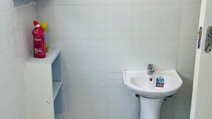 A small bathroom with a white sink, a white cabinet, and a blue and white patterned floor.