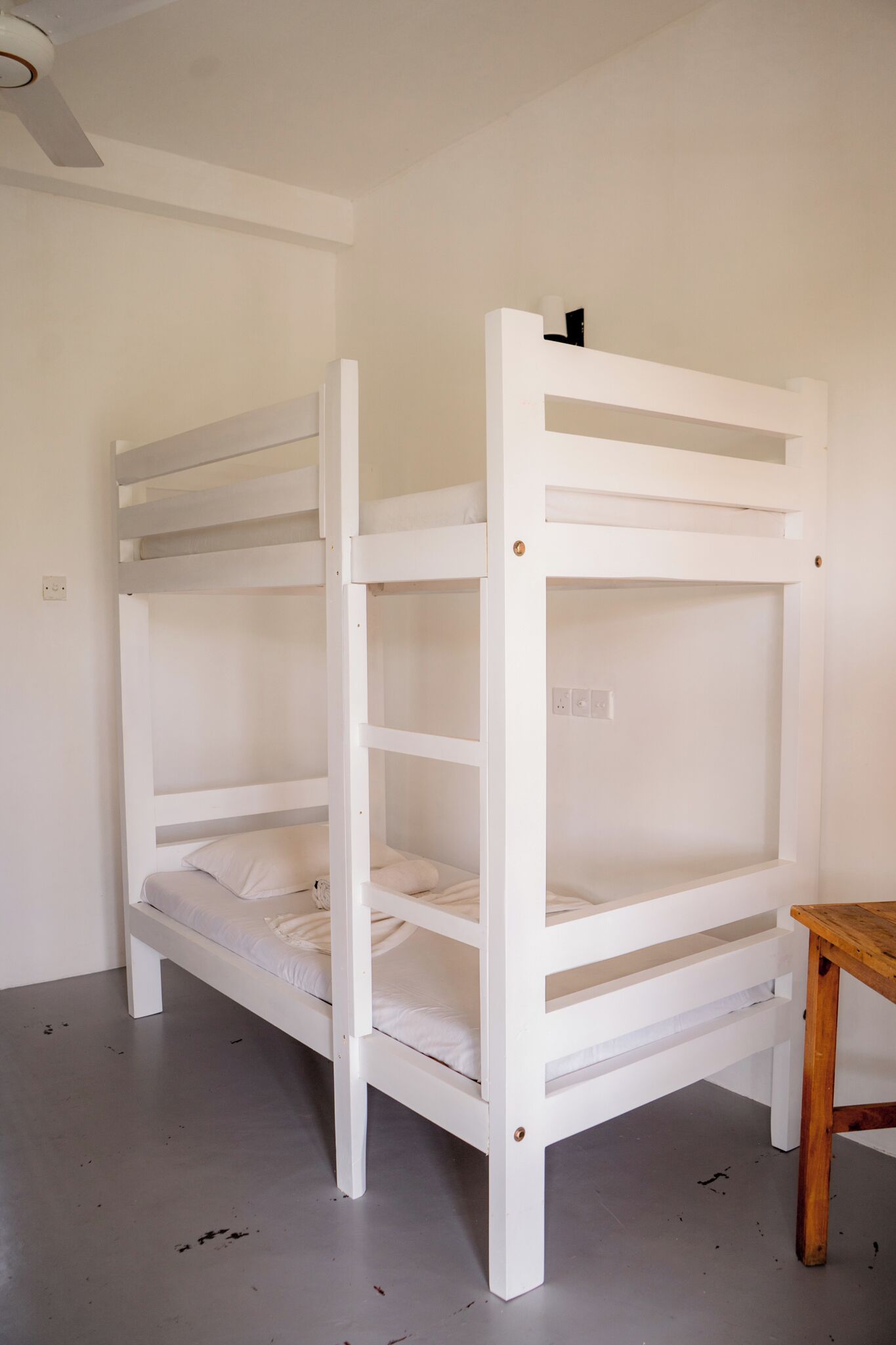Una cama individual superpuesta con una mesa de madera a su lado.