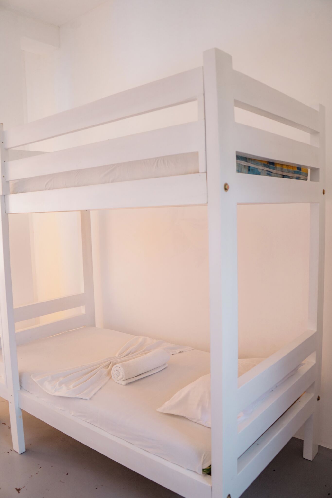 A white bunk bed with a small shelf on the top bunk.