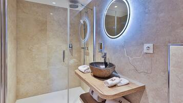 Un bagno moderno con cabina doccia in vetro, un mobile bagno in legno con lavabo a incasso e uno specchio grande.