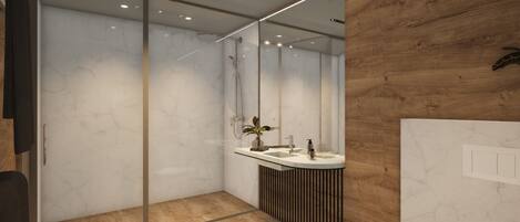 Un baño moderno con cabina de ducha de vidrio, tocador de madera con lavabo y espejo.