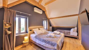 Une chambre avec deux lits, des poutres en bois, une fenêtre et un appareil de climatisation.