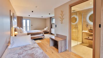 Une chambre d’hôtel moderne dotée d’un grand lit, d’un lit plus petit, d’un bureau, d’une douche séparée par une paroi de verre et offrant une vue sur l’extérieur.