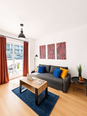 A modern living room with a sofa, coffee table, and artwork on the wall. - Lumina stylish 3-room apart near Atlas Arena (Łódź)