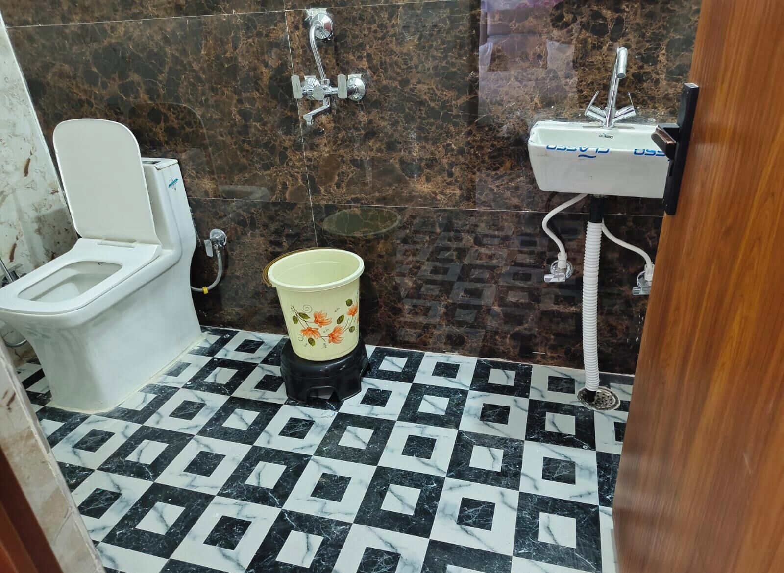 A bathroom with a toilet, a sink, and a trash bin.