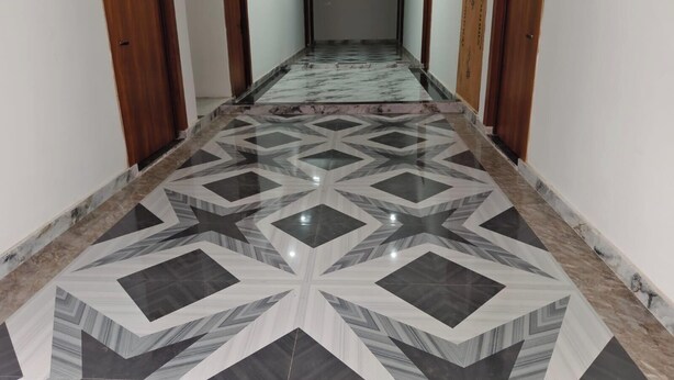 Un pasillo con suelo de estampado geométrico, puertas de madera y una pared lisa.