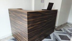 Un mostrador de recepción con acabado de madera oscura y un ordenador portátil encima.