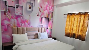 Un dormitorio con cama, mesitas de noche, una pared decorada con motivos florales y mariposas, una ventana con cortinas y suelo de mármol.