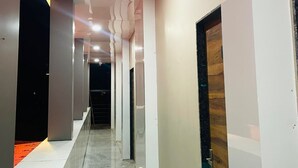 Un pasillo moderno con piso pulido, paredes blancas y una puerta de madera a la derecha.