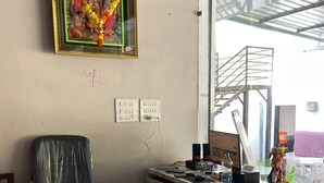 Un mostrador de recepción con encimera de mármol, un cuadro religioso enmarcado encima y una silla a la izquierda.
