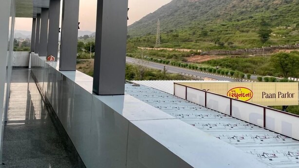 Un edificio moderno con una galería techada y vistas a un paisaje montañoso.