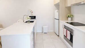A modern kitchen with white cabinetry, a central island, a built-in oven, and a sink.