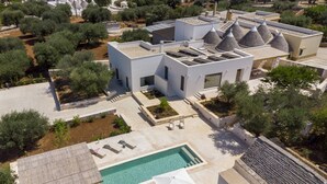 Une villa moderne dotée d’une piscine, d’un espace salon extérieur et d’un jardin.
