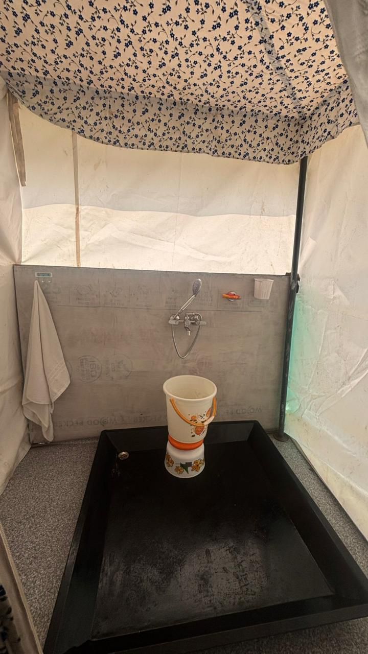 Une salle de bain avec un lavabo noir, une douche et une serviette accrochée au mur.