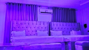 A bedroom with a large bed, a bedside table, and an air conditioning unit. - KINGSAMYSTAR HOTEL AND SUITES  (Asaba)