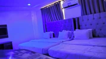 A hotel room with two beds, a flat-screen TV, and an air conditioning unit.