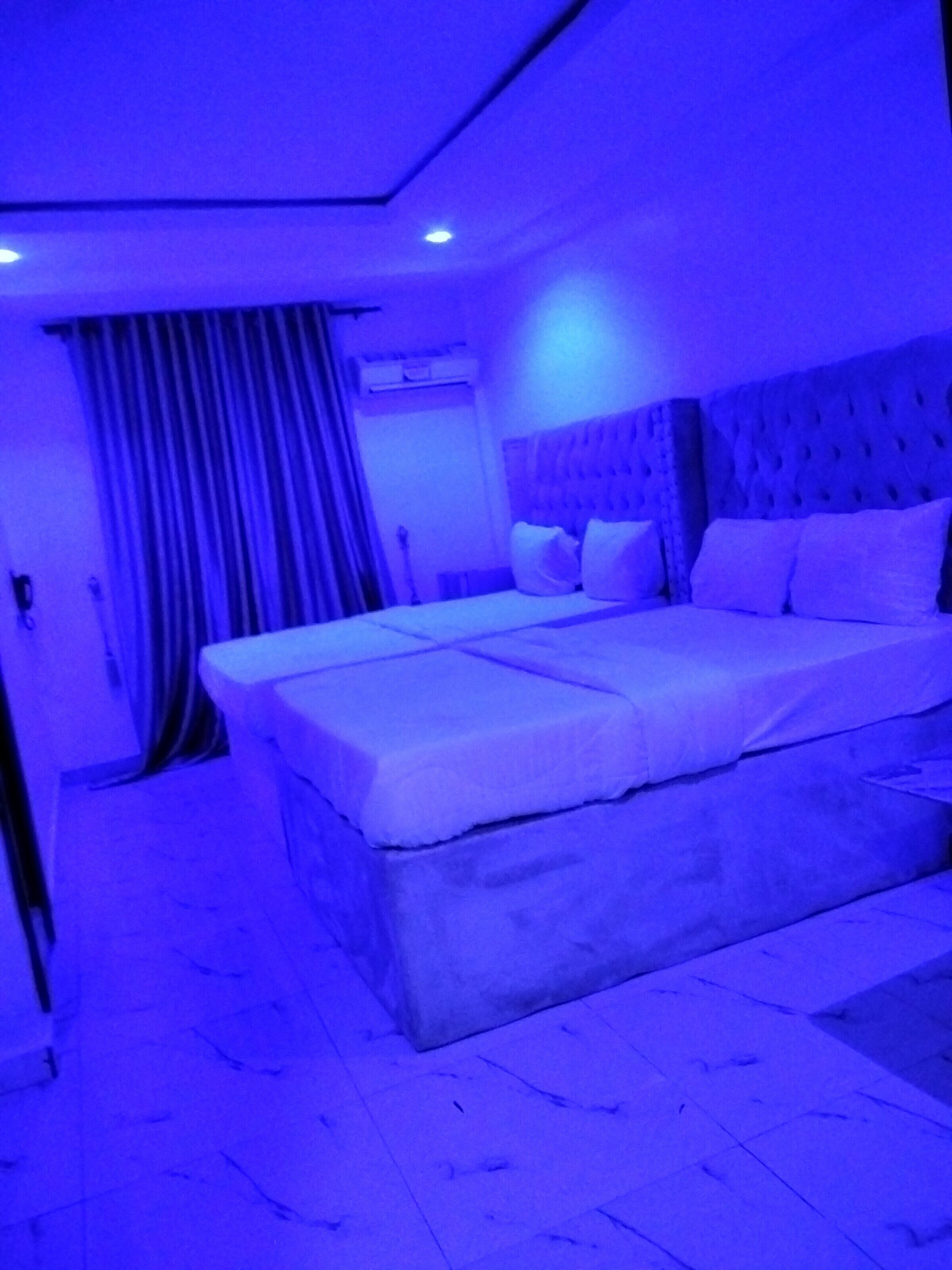 A room with a large bed, a headboard, and a curtain.